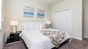 A bedroom with a bed, nightstands, a ceiling fan, and two wall-mounted pictures.