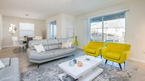 A modern living room with a grey sofa, yellow armchairs, a white coffee table, and large windows.