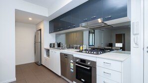 Una cocina moderna con electrodomésticos de acero inoxidable, armarios blancos y horno empotrado.