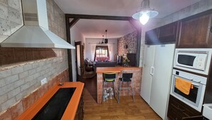 A kitchen with a brick wall, a gas stove, a microwave, and a refrigerator.