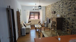 A living room with a sofa, a coffee table, a TV, and a stone-patterned wall.