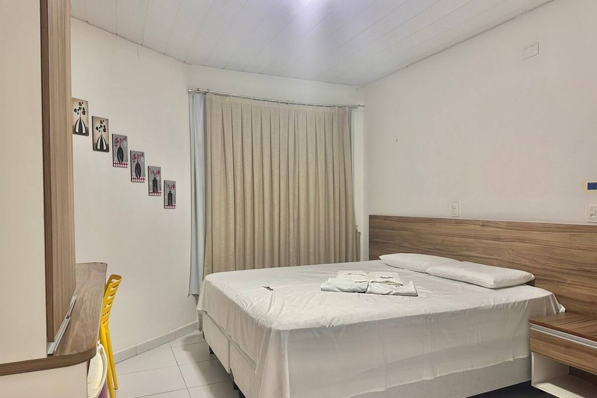 Een netjes ingerichte hotelkamer met een bed, een houten nachtkastje en een wandplank.