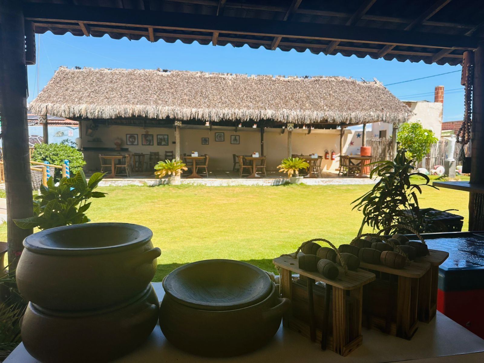 Una casa con techo de paja, césped y zona de estar al aire libre.