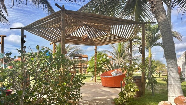 Un espacio al aire libre cubierto con un sendero de piedra que lleva a una zona de estar bajo una pérgola de madera.