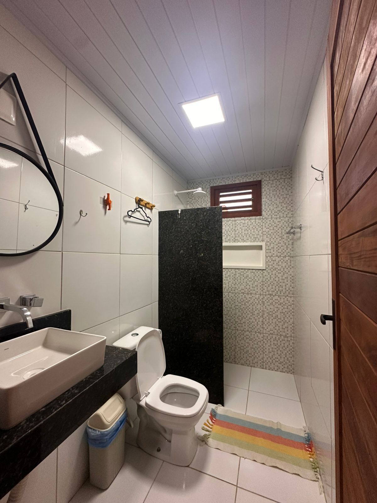 A compact bathroom with a white toilet, a black marble sink, and a mirror.