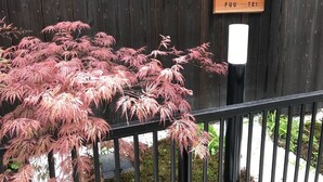 A wooden fence with a sign that reads "FUU TEI" and a tree with pink foliage in front of it. - Fuu Tei (Kyoto)