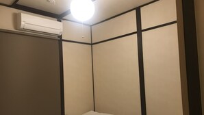 A small, compact room with a single bed, a ceiling light, and an air conditioning unit. - Fuu Tei (Kyoto)