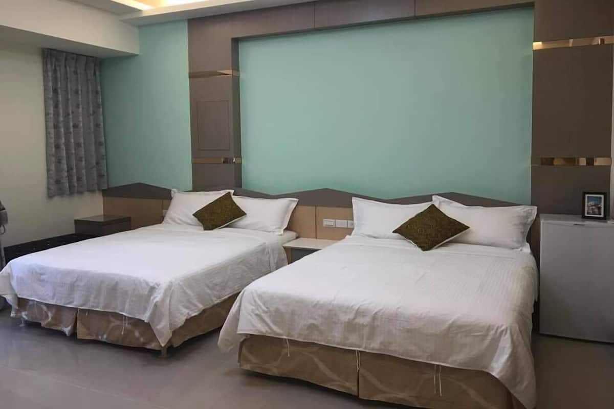 A hotel room with two beds, a large window, and a flat-screen TV.