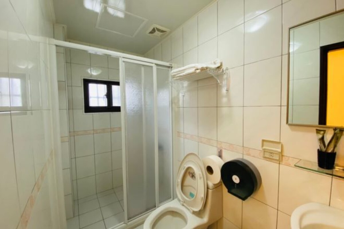 A bathroom with a toilet, a glass shower enclosure, and a sink with a mirror.