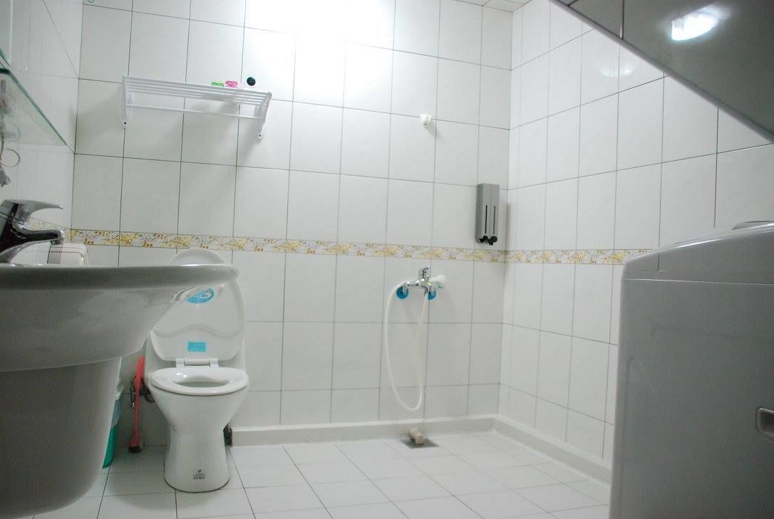 Casa de banho com sanita, lavatório e chuveiro.