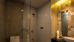 A modern bathroom with a glass-enclosed shower, a toilet, and a sink with a mirror. - Sky Hotel Pampanga (Bacolor)