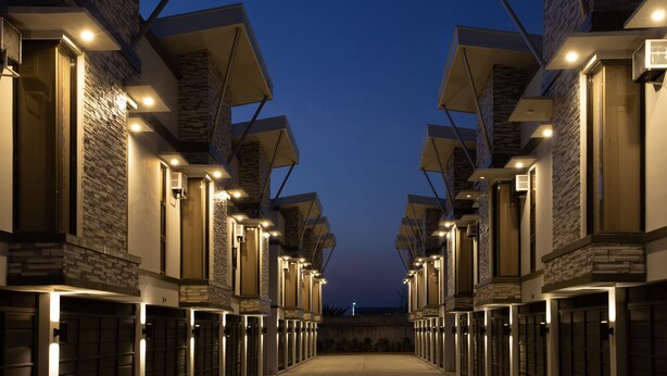 A row of modern hotel rooms with stone facades and large windows, connected by a central corridor. - Sky Hotel Pampanga (Bacolor)
