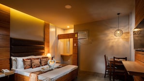 A modern bedroom with a wooden bed, bedside table, and a small desk with a chair. - Sky Hotel Pampanga (Bacolor)