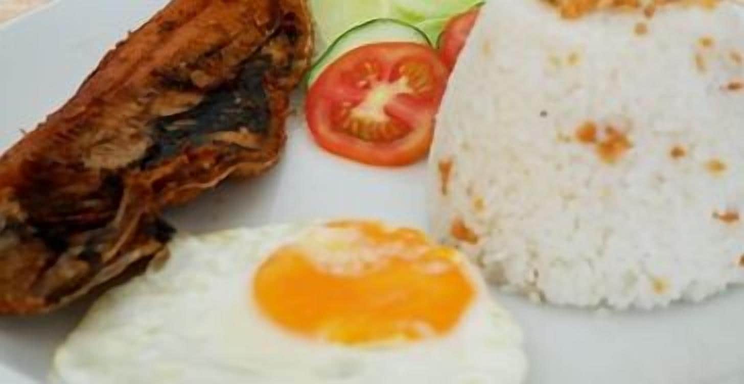 A plate with fried chicken, a fried egg, white rice, and a slice of tomato.