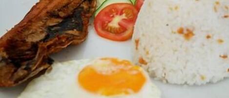 A plate with fried chicken, a fried egg, white rice, and a slice of tomato.