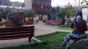 A plaza with benches, a statue, and a building with a sign.