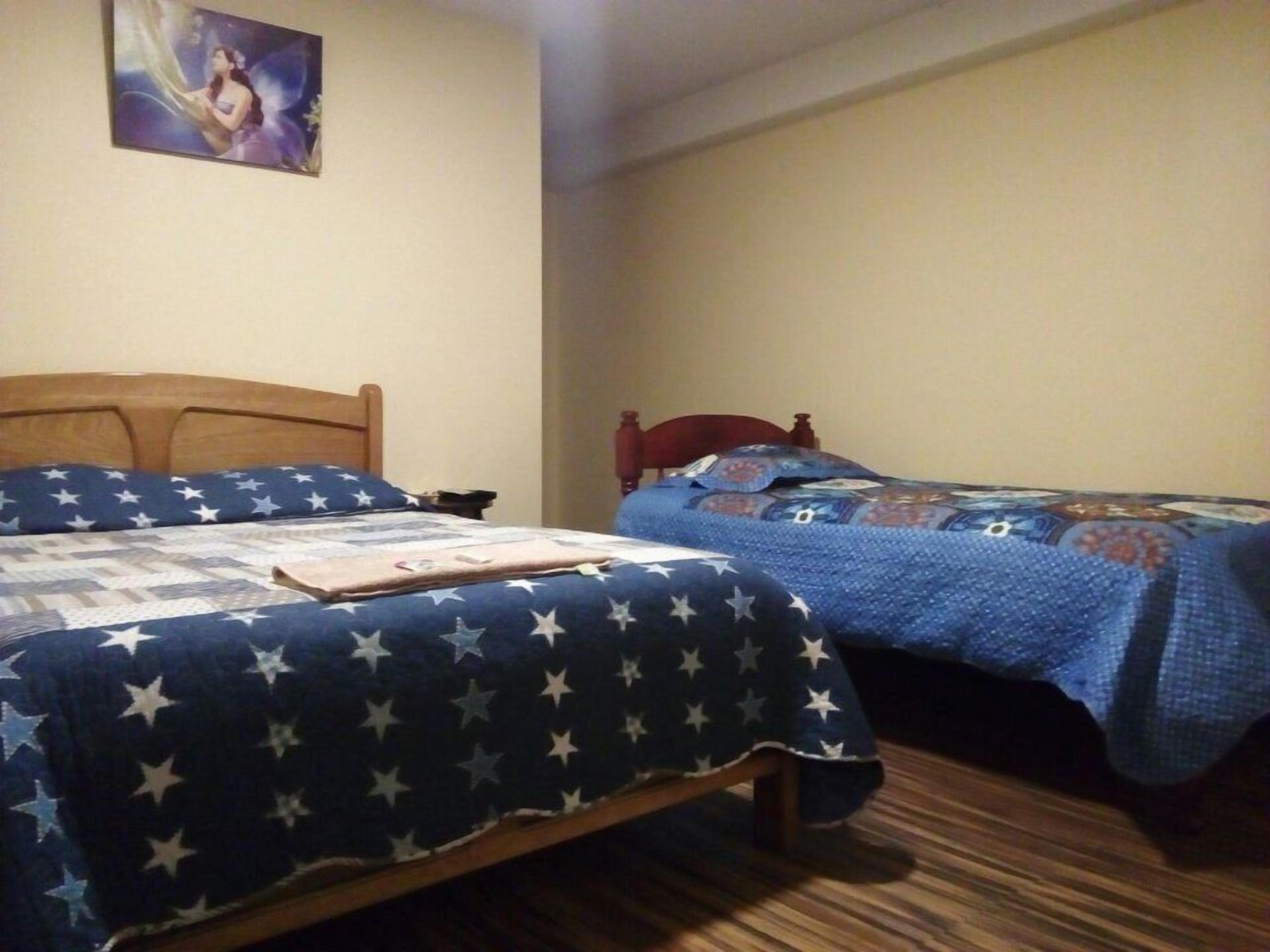 A room with two beds, each with a star-patterned bedspread.