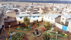 A residential area with a central plaza featuring a fountain and benches, surrounded by houses with varied roof styles.