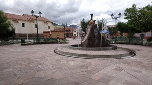 A public square with a central fountain, paved with stone tiles, surrounded by buildings with traditional architecture.