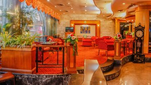 A lobby with red seating, a large clock, and a TV on a wall. - Yannaty Hotel Halal (Hat Yai)