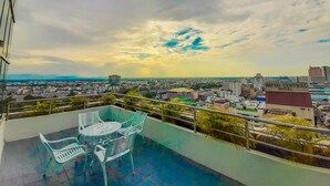 A rooftop terrace with a table and chairs, overlooking a cityscape with buildings and a hotel named "Hathai Central Hotel". - Yannaty Hotel Halal (Hat Yai)
