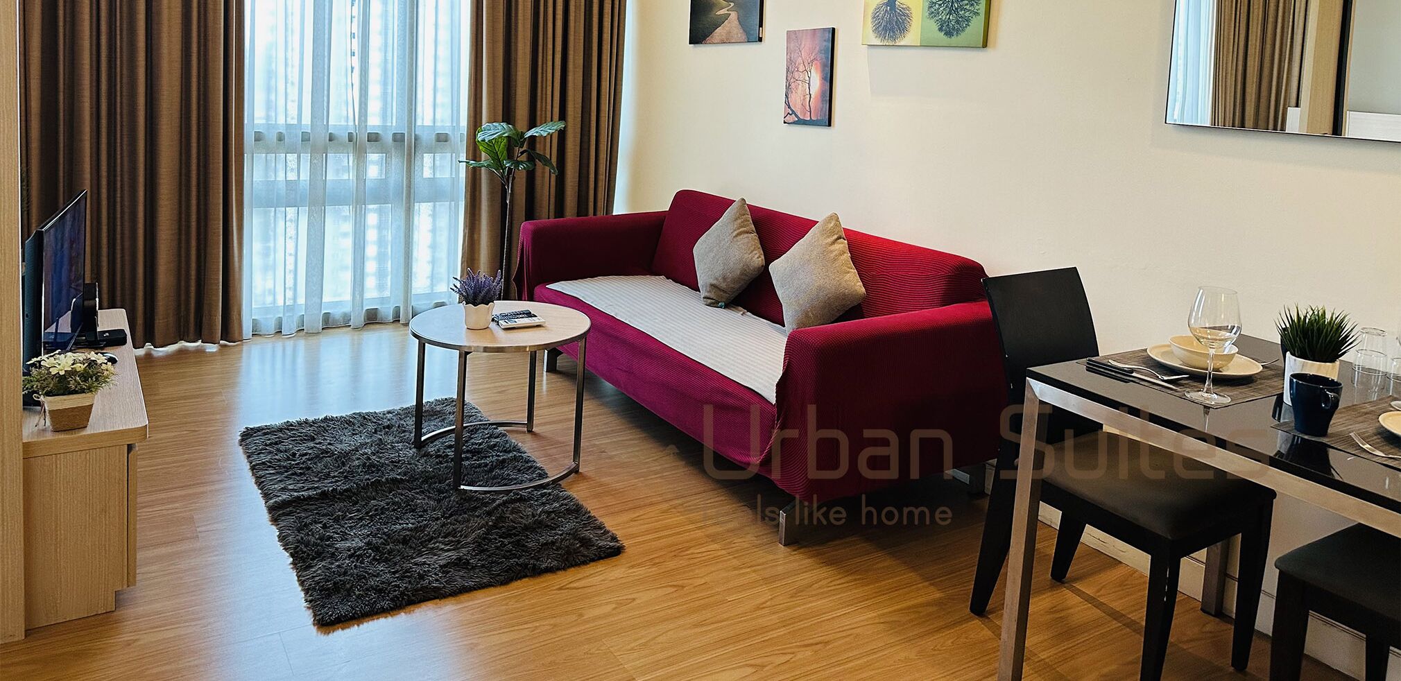 Un salon moderne avec un canapé rouge, une petite table ronde et un coin repas comprenant une table et des chaises noires.