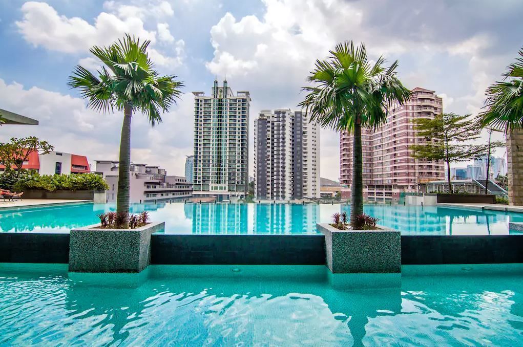A pool with palm trees, surrounded by high-rise buildings.