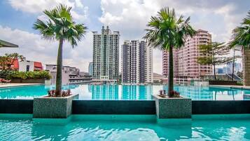 A pool with palm trees, surrounded by high-rise buildings.