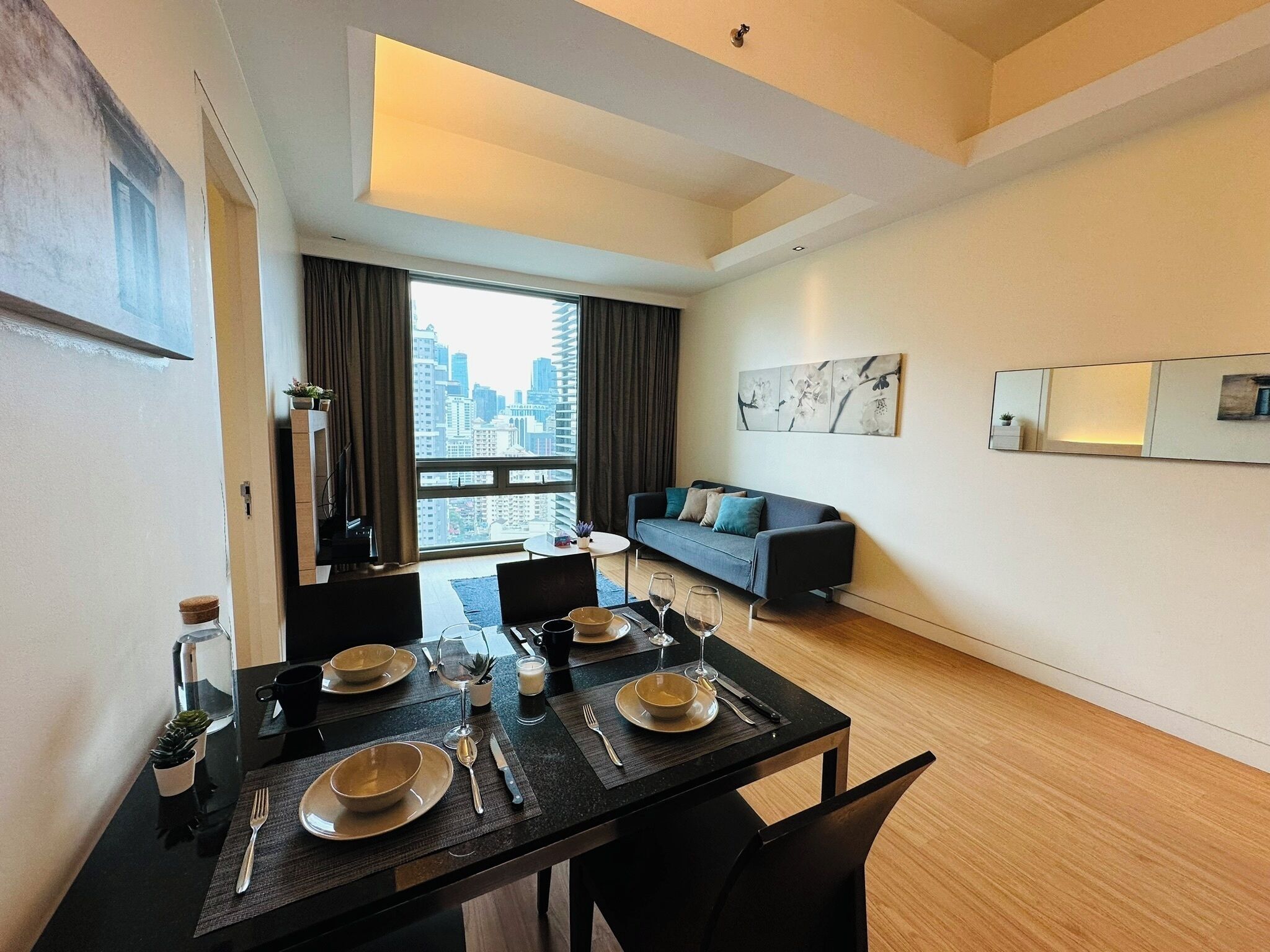 A modern living room with a dining area, a sofa, and a city view.