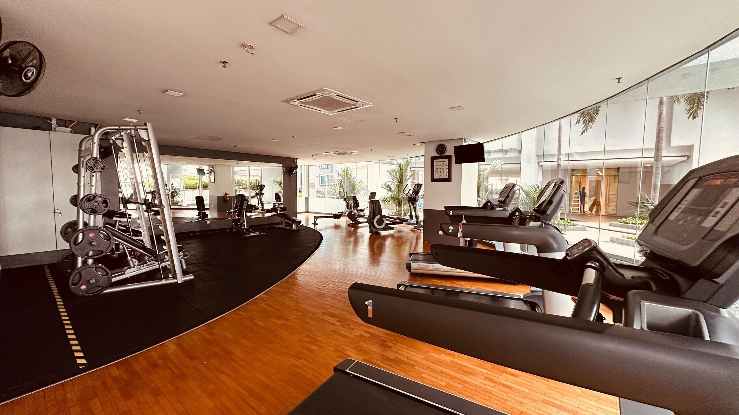 A gym with cardio machines, weightlifting equipment, and a large mirror.
