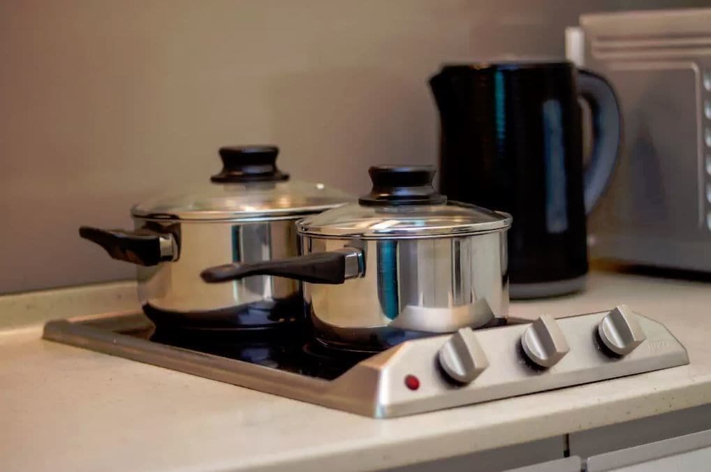 A kitchen with two stainless steel pots on a stove, a black coffee maker, and a white oven.
