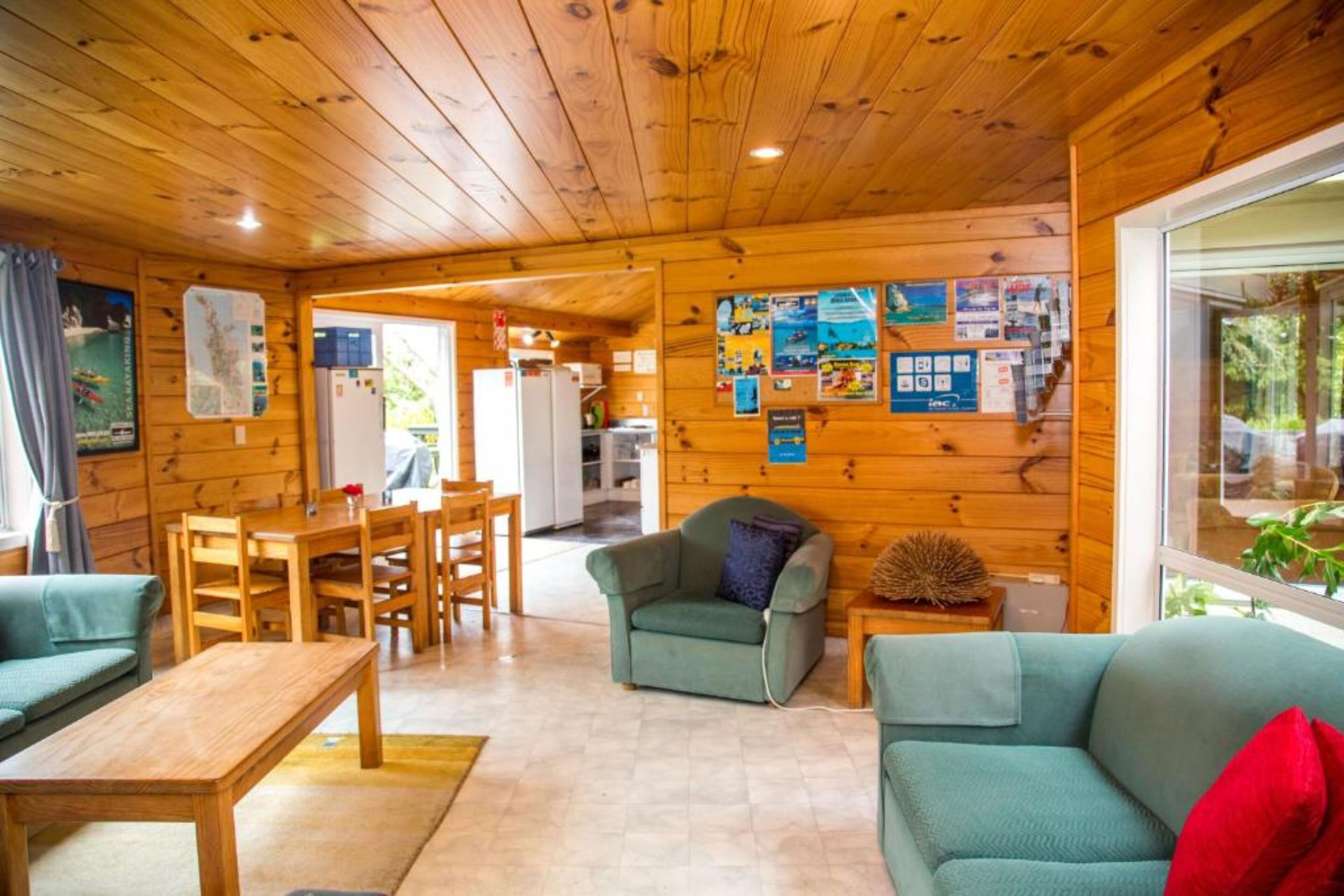 A wooden cabin interior with a dining area, a sofa, and a small table.
