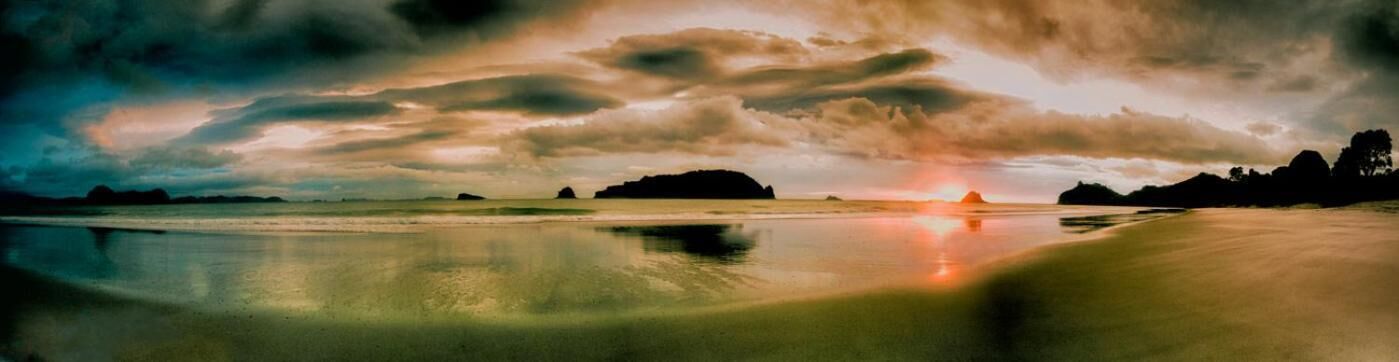 Een strand met een zonsondergang en wolken.