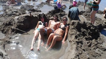 A sandy beach with people sitting and standing in the water.