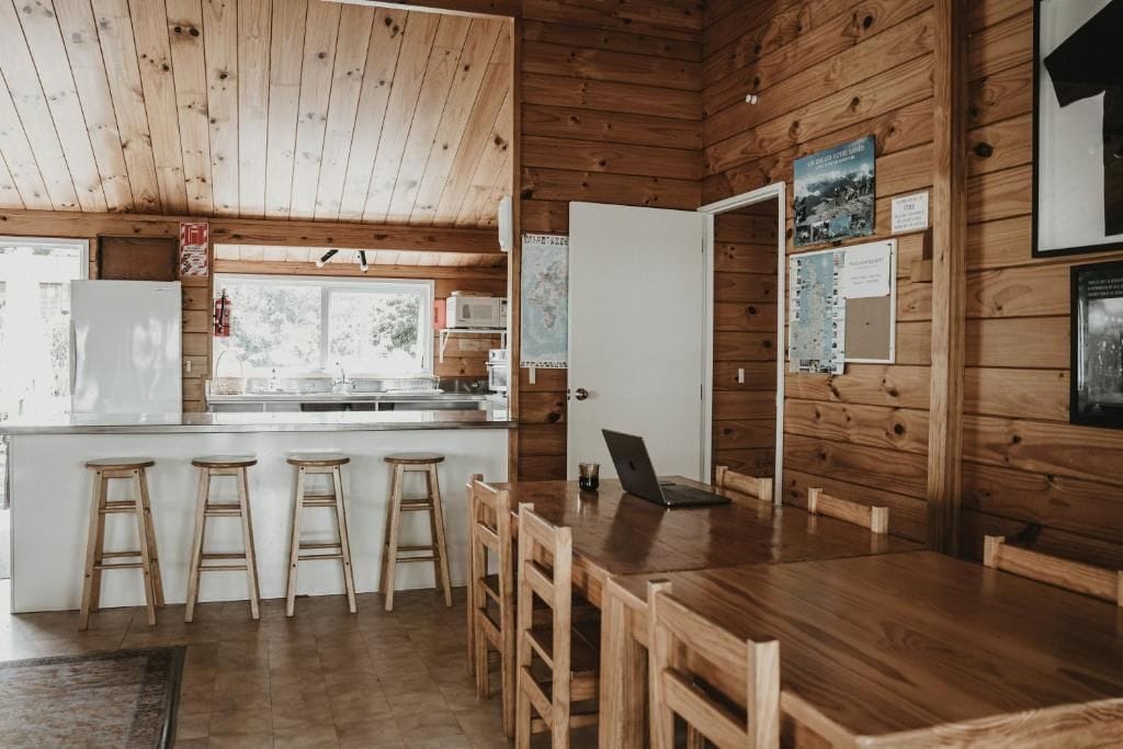 Un intérieur en bois comprenant une cuisine, des tabourets de bar et une table à manger.
