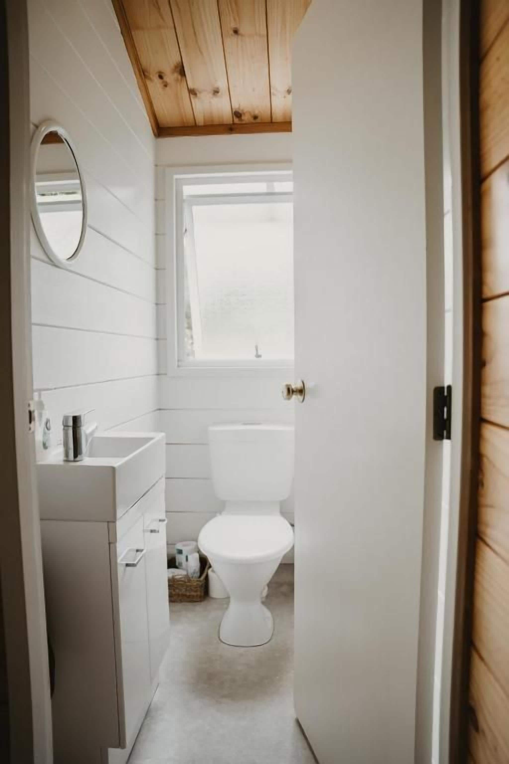 Un baño con inodoro, lavamanos y espejo.
