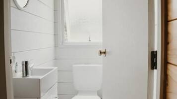 Un baño con inodoro, lavamanos y espejo.