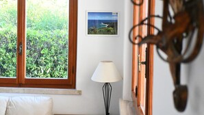 Una habitación con un ventanal grande, un cuadro enmarcado, una lámpara y un adorno de madera en la pared.