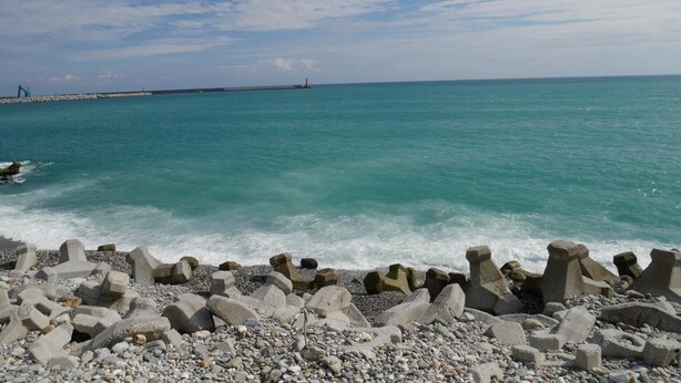 A coastal scene with a rocky shoreline and a breakwater extending into the sea. - Heyyo Hostel (Hualien City)