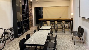 A conference room with a long table, chairs, a projector, and a bike parked outside. - Heyyo Hostel (Hualien City)