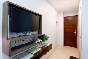 A reception area with a flat-screen TV mounted on a wooden console, a telephone, and a small potted plant. - The Rooms by Alinace at Mango (Cebu City)
