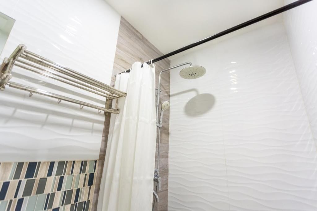 Eine Dusche mit Duschbrause und Handtuchhalter.
