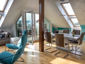 Un appartement moderne de style « loft », comprenant un coin repas, un canapé et une grande fenêtre.