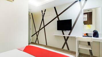 A hotel room with a bed, a desk, a chair, a TV, and a mirror.