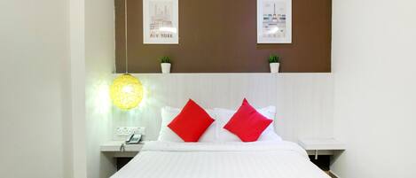 Una habitación de hotel con una cama, una mesita de noche, una lámpara y dos cuadros colgados en la pared.