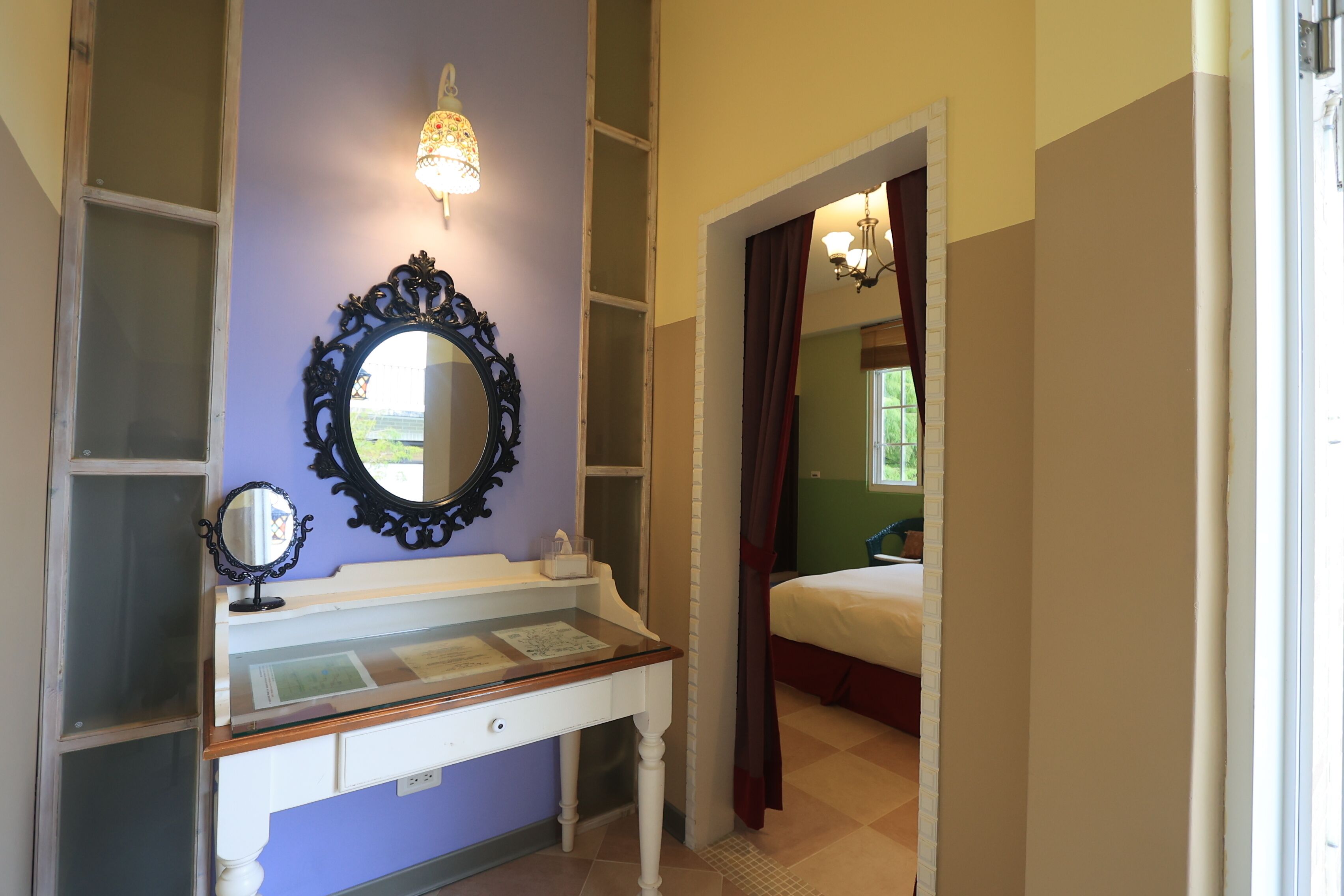 A bedroom with a bed, a dresser with a mirror, and a window with curtains.
