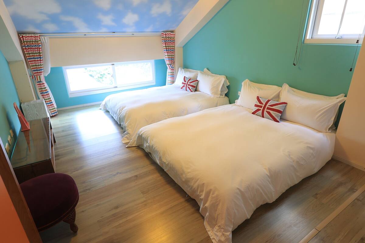 Quarto com duas camas, janela com cortinas, escrivaninha e uma cadeira.
