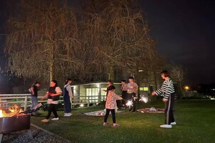 Un grupo de personas reunidas alrededor de un brasero al aire libre de noche.
