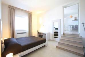 Een moderne hotelkamer met een bed, bureau, stoel en een trap naar een hoger niveau.