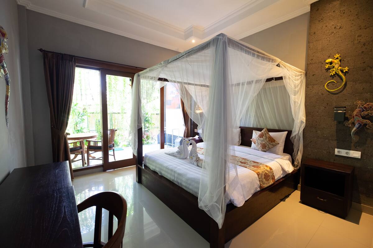 A bedroom with a four-poster bed, a dining table, and a chair.